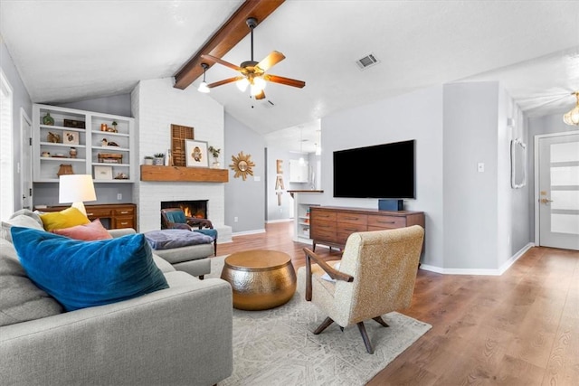 living room featuring wood-type flooring, lofted ceiling with beams, a brick fireplace, and ceiling fan