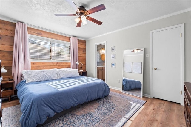 bedroom featuring ensuite bathroom, crown molding, light hardwood / wood-style flooring, ceiling fan, and a textured ceiling