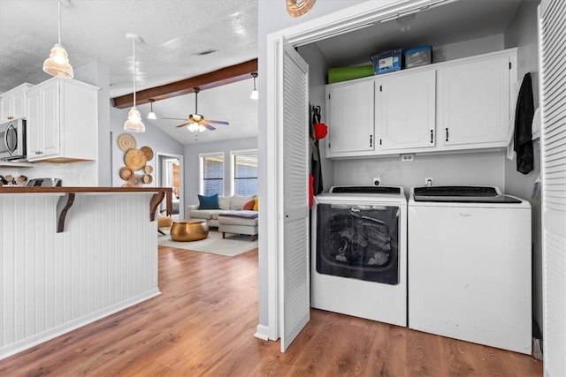 clothes washing area featuring washing machine and dryer, ceiling fan, cabinets, and hardwood / wood-style flooring