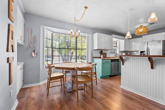 kitchen featuring white cabinets, pendant lighting, stainless steel appliances, and dark hardwood / wood-style floors