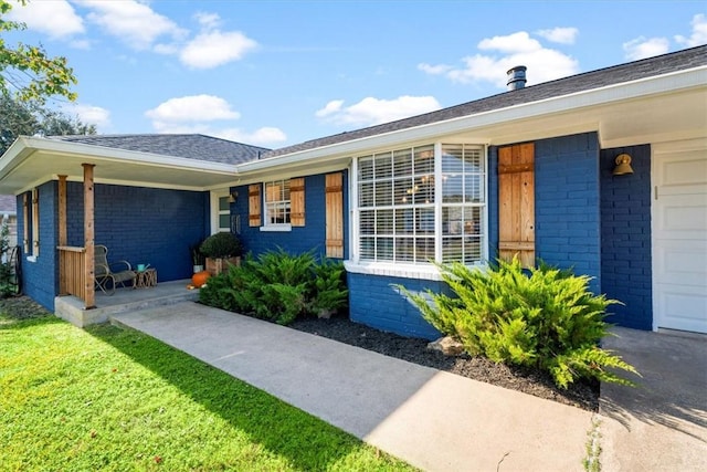 entrance to property featuring a garage and a lawn