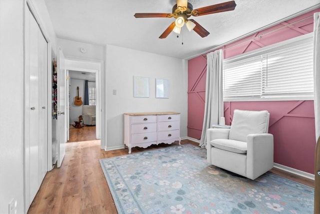 living area featuring ceiling fan, light hardwood / wood-style flooring, and a healthy amount of sunlight