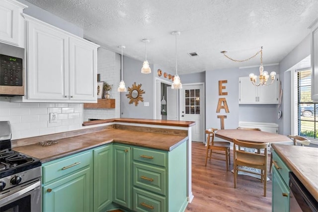 kitchen with white cabinetry, hanging light fixtures, and stainless steel appliances