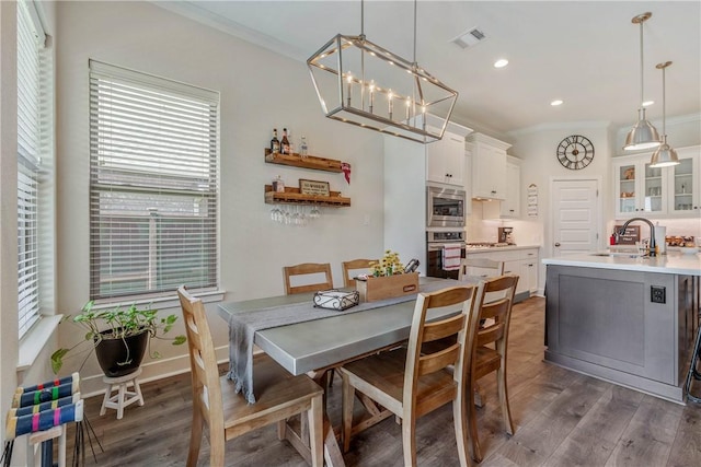 dining area featuring dark hardwood / wood-style floors, a wealth of natural light, ornamental molding, and sink