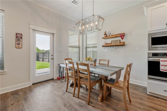 dining space featuring a healthy amount of sunlight, crown molding, and hardwood / wood-style floors