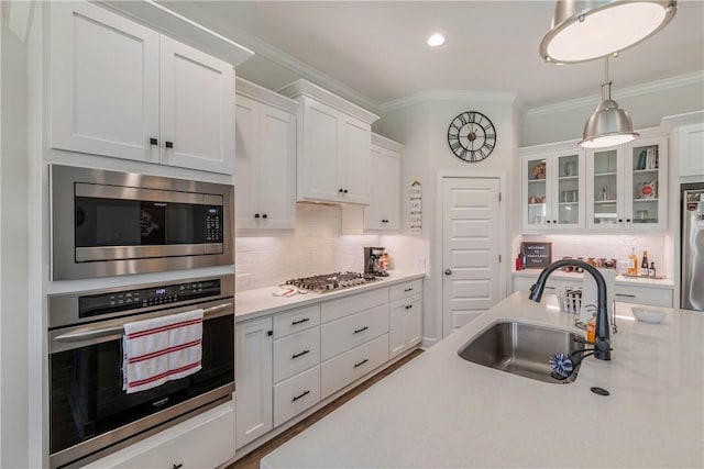 kitchen with sink, appliances with stainless steel finishes, tasteful backsplash, decorative light fixtures, and white cabinetry