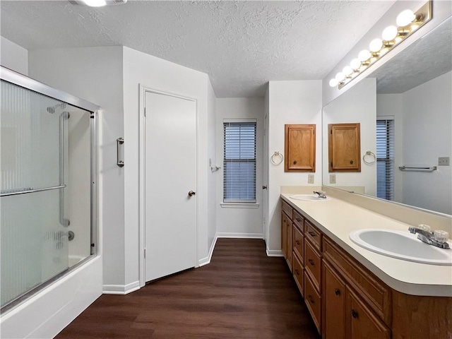 bathroom with hardwood / wood-style floors, vanity, enclosed tub / shower combo, and a textured ceiling