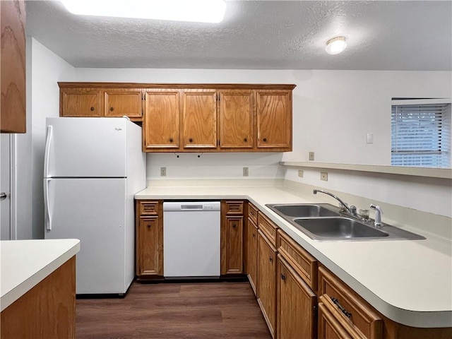 kitchen with kitchen peninsula, dark hardwood / wood-style flooring, a textured ceiling, white appliances, and sink