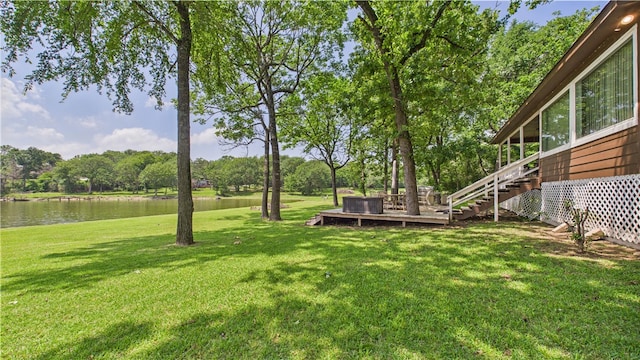 view of yard featuring stairs and a deck with water view