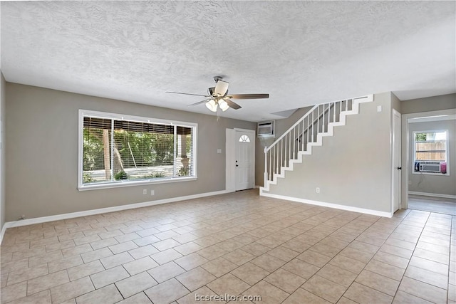 unfurnished living room with ceiling fan, light tile patterned flooring, a textured ceiling, and a wealth of natural light