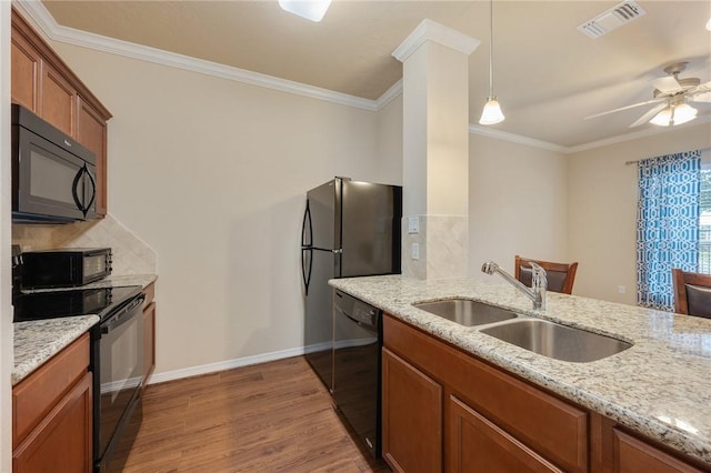 kitchen with sink, light stone counters, hanging light fixtures, hardwood / wood-style floors, and black appliances