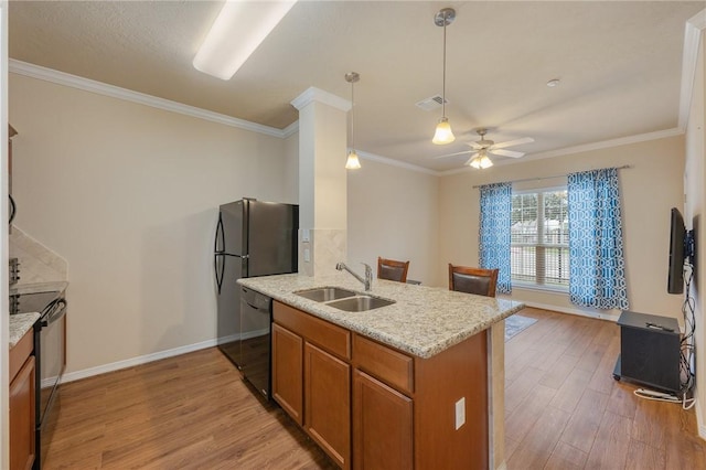 kitchen featuring sink, ornamental molding, light hardwood / wood-style floors, black appliances, and light stone countertops