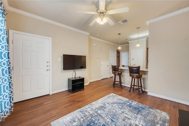 living room featuring ceiling fan, ornamental molding, and wood-type flooring