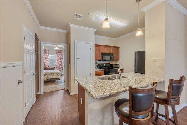 kitchen with sink, a breakfast bar area, hanging light fixtures, kitchen peninsula, and black appliances