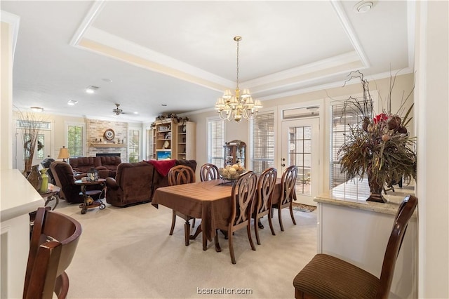 4718 Stonebriar Cir, College Station, TX 77845 - carpeted dining space featuring ceiling fan with notable chandelier, a large fireplace, a raised ceiling, and ornamental molding