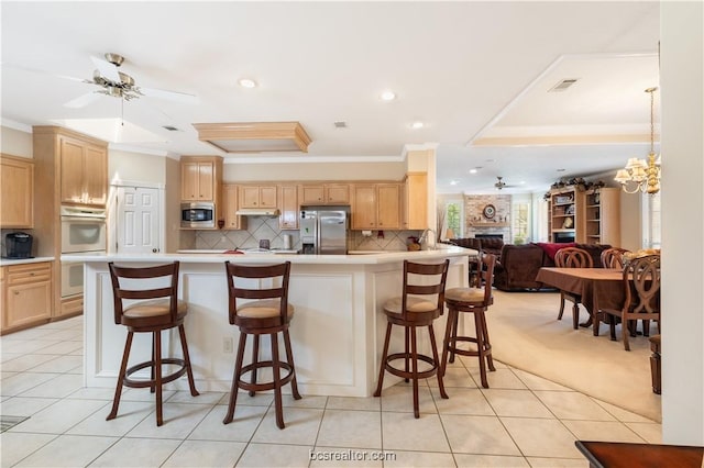 4718 Stonebriar Cir, College Station, TX 77845 - kitchen with light brown cabinets, a kitchen bar, ornamental molding, and appliances with stainless steel finishes