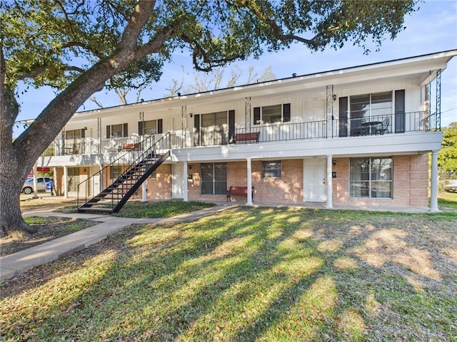 view of front of home with stairs, a front lawn, and brick siding