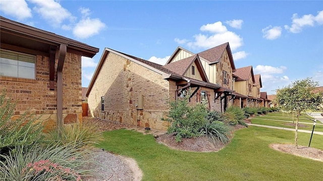 view of home's exterior featuring board and batten siding, brick siding, a yard, and a shingled roof