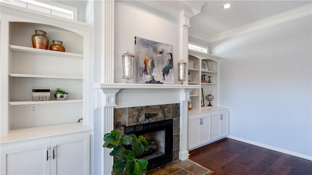 living area featuring baseboards, dark wood finished floors, built in features, ornamental molding, and a fireplace