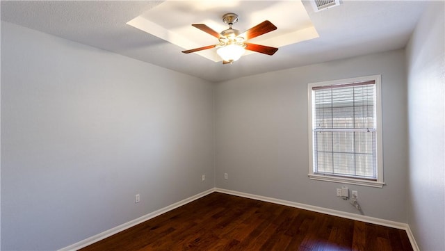 unfurnished room with visible vents, baseboards, dark wood-type flooring, and a ceiling fan