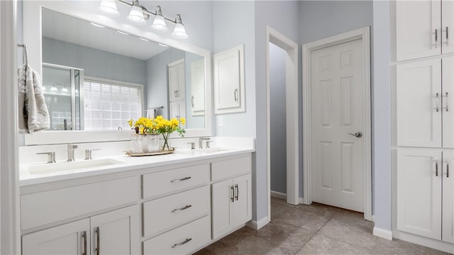 bathroom featuring double vanity, baseboards, and a sink