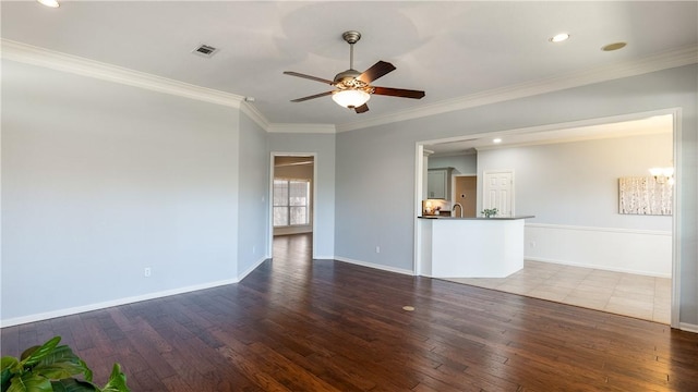 unfurnished living room with baseboards, visible vents, ceiling fan, wood-type flooring, and crown molding