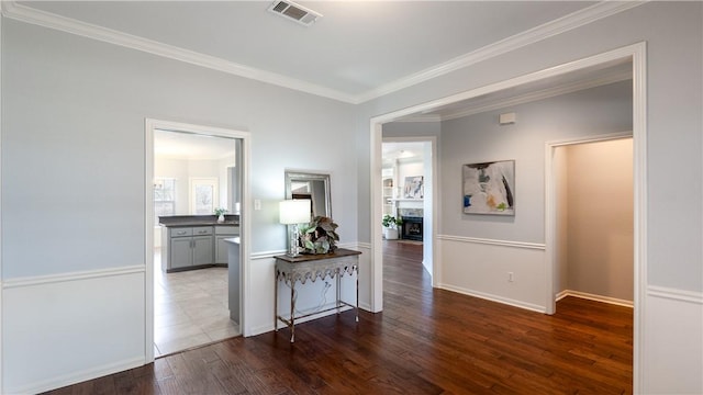 hall with visible vents, crown molding, baseboards, and wood-type flooring