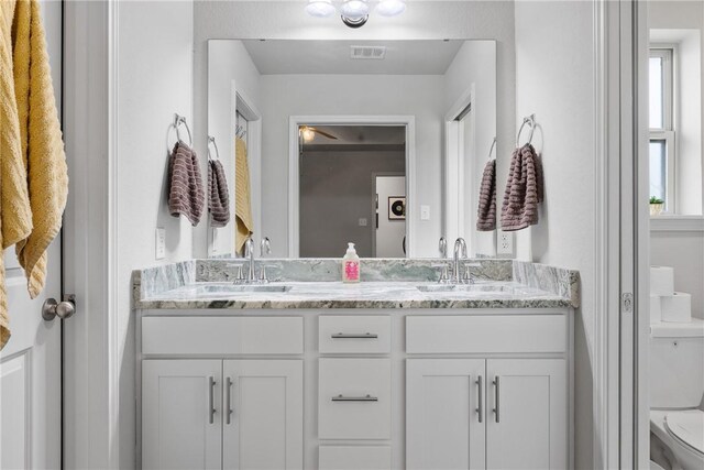 full bathroom featuring visible vents, a sink, double vanity, and toilet