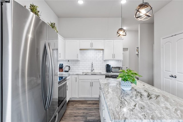 kitchen with a sink, appliances with stainless steel finishes, white cabinetry, dark wood-style flooring, and light stone countertops