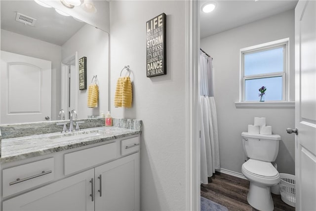 bathroom with wood finished floors, visible vents, toilet, vanity, and baseboards