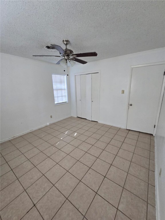 tiled spare room with ceiling fan and a textured ceiling