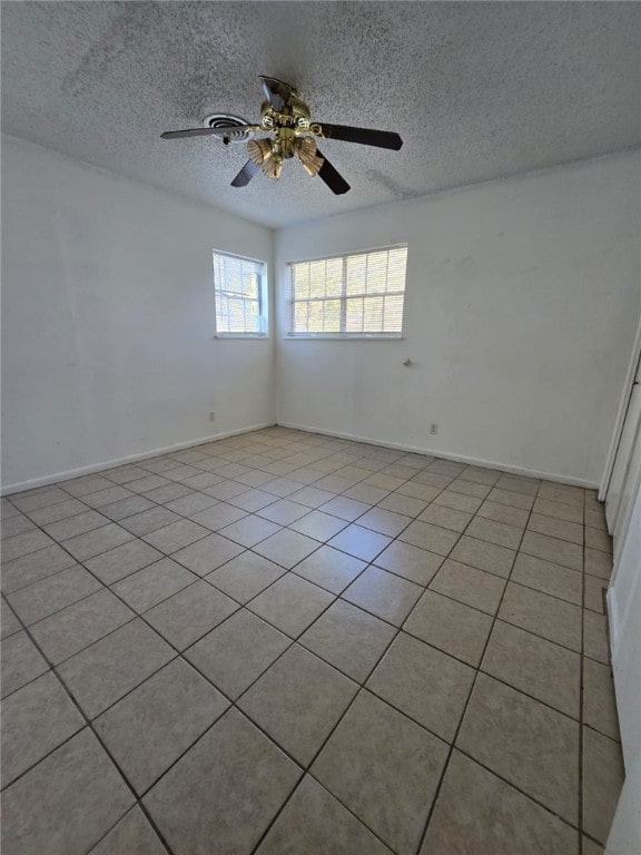 unfurnished room featuring ceiling fan, light tile patterned floors, and a textured ceiling