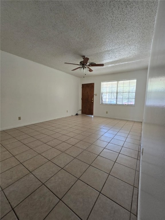 empty room with a textured ceiling, ceiling fan, and light tile patterned flooring