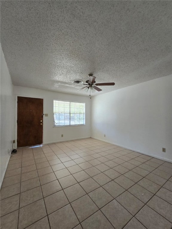 empty room featuring light tile patterned floors, a textured ceiling, and ceiling fan