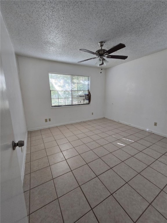 spare room featuring ceiling fan, light tile patterned flooring, and a textured ceiling