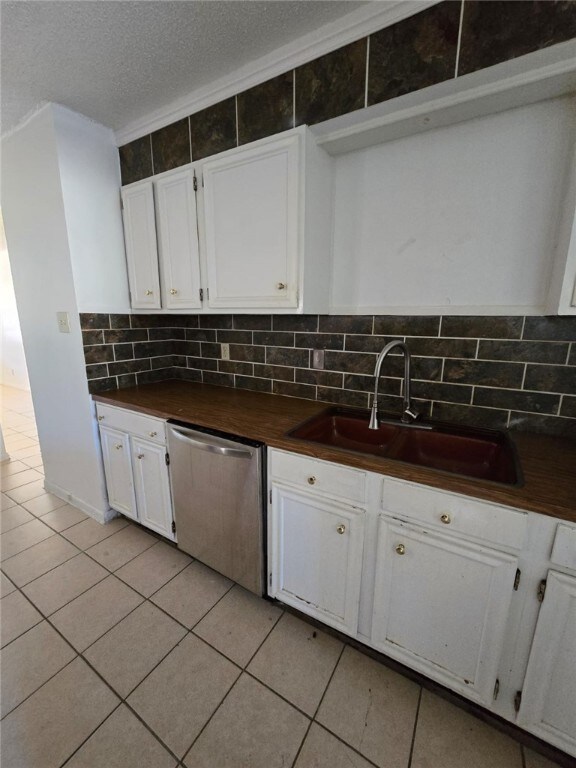 kitchen featuring white cabinetry, sink, stainless steel dishwasher, and a textured ceiling