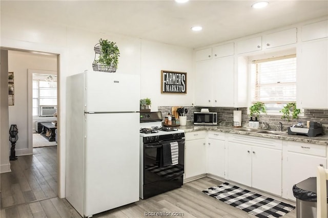 kitchen with white cabinetry, black gas range oven, tasteful backsplash, white refrigerator, and light hardwood / wood-style floors