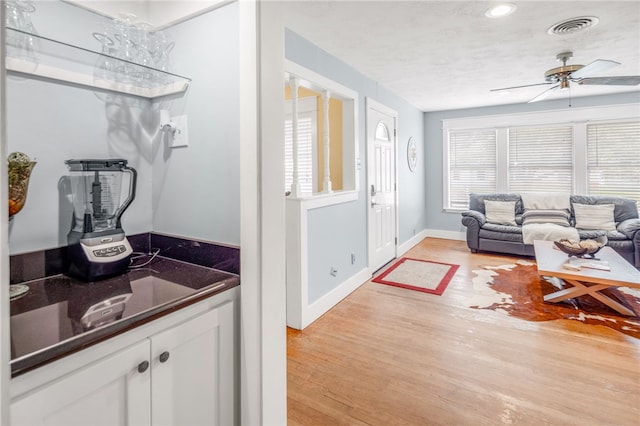 interior space with white cabinetry, a textured ceiling, light hardwood / wood-style flooring, and ceiling fan