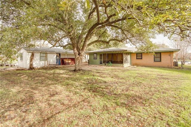 rear view of house featuring a sunroom and a yard