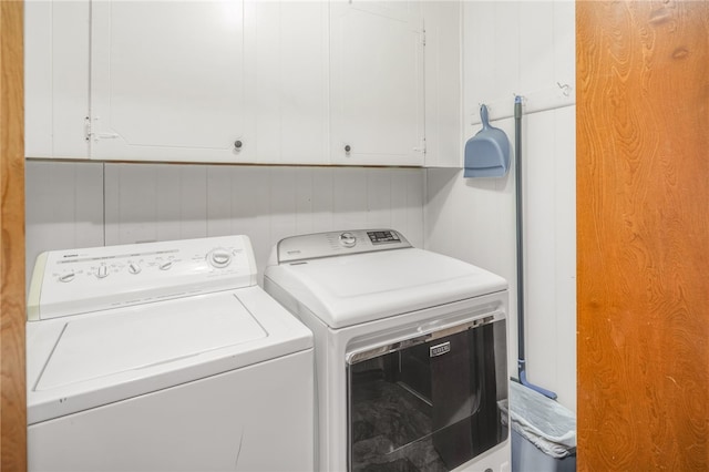 clothes washing area with cabinets and separate washer and dryer