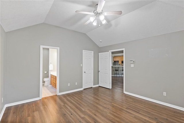 unfurnished bedroom featuring connected bathroom, dark hardwood / wood-style floors, vaulted ceiling, and ceiling fan