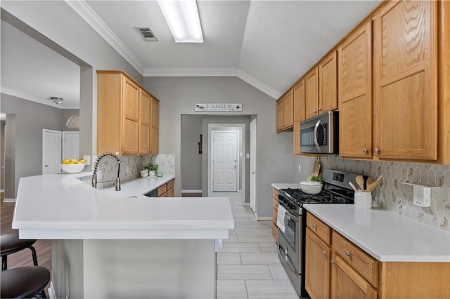 kitchen featuring a kitchen breakfast bar, crown molding, vaulted ceiling, appliances with stainless steel finishes, and kitchen peninsula