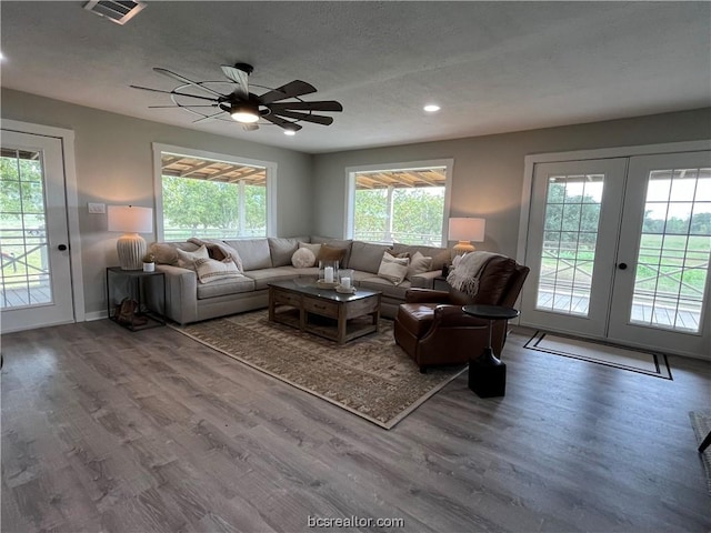 living room with a wealth of natural light, french doors, ceiling fan, and hardwood / wood-style flooring