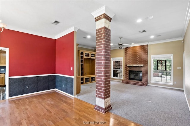 unfurnished living room featuring hardwood / wood-style floors, ceiling fan, ornate columns, and ornamental molding