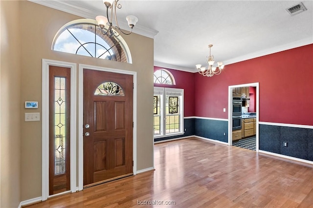 entrance foyer featuring wood-type flooring, an inviting chandelier, and ornamental molding