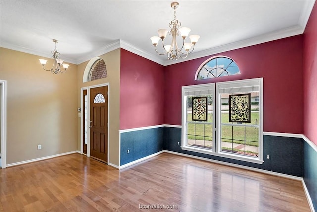 entrance foyer with wood-type flooring, ornamental molding, and a chandelier