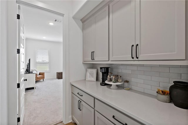 bar with visible vents, tasteful backsplash, baseboards, and light carpet