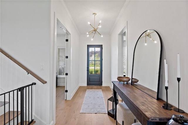 foyer entrance with a chandelier, baseboards, light wood-style flooring, and crown molding