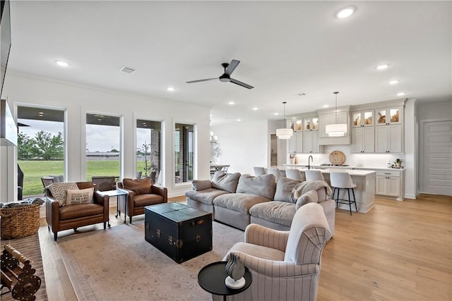 living room featuring recessed lighting, ornamental molding, ceiling fan, light wood finished floors, and visible vents