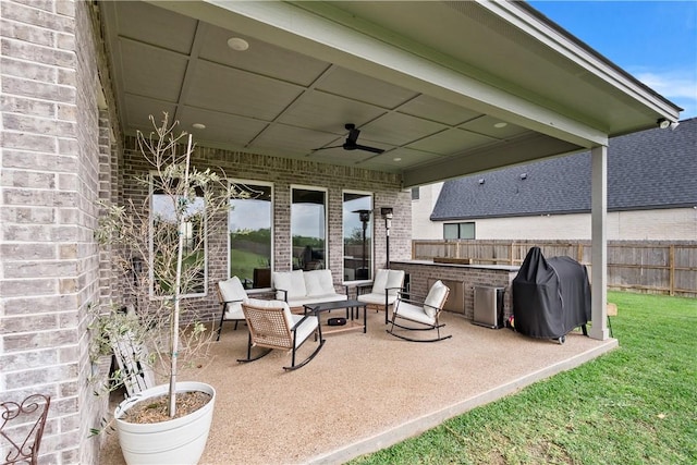 view of patio featuring fence, area for grilling, a ceiling fan, and an outdoor living space